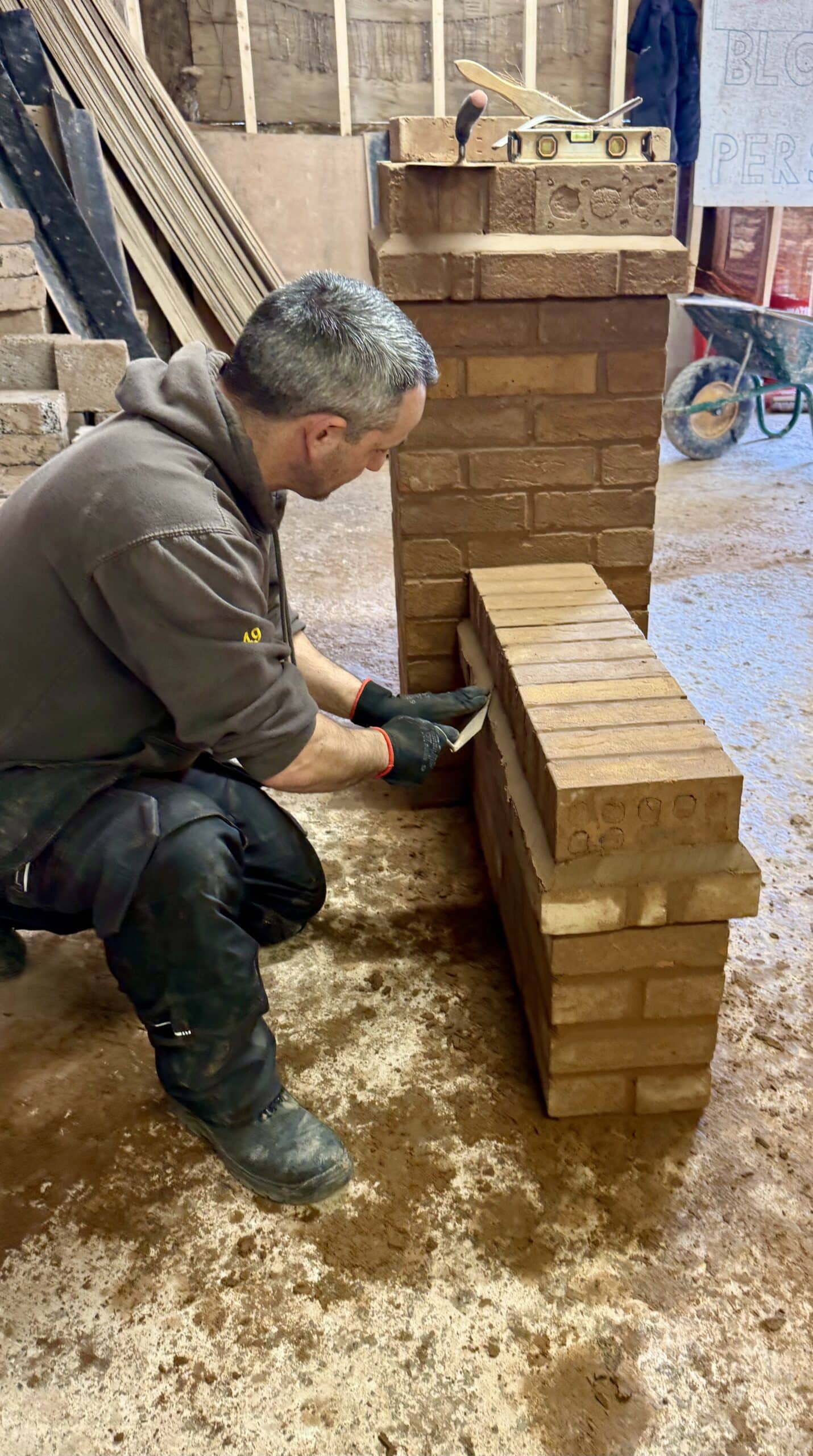 Person finishing off brick wall and attached pillar