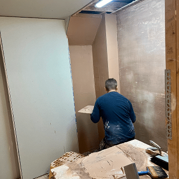 Person on a plastering course skimming his bay