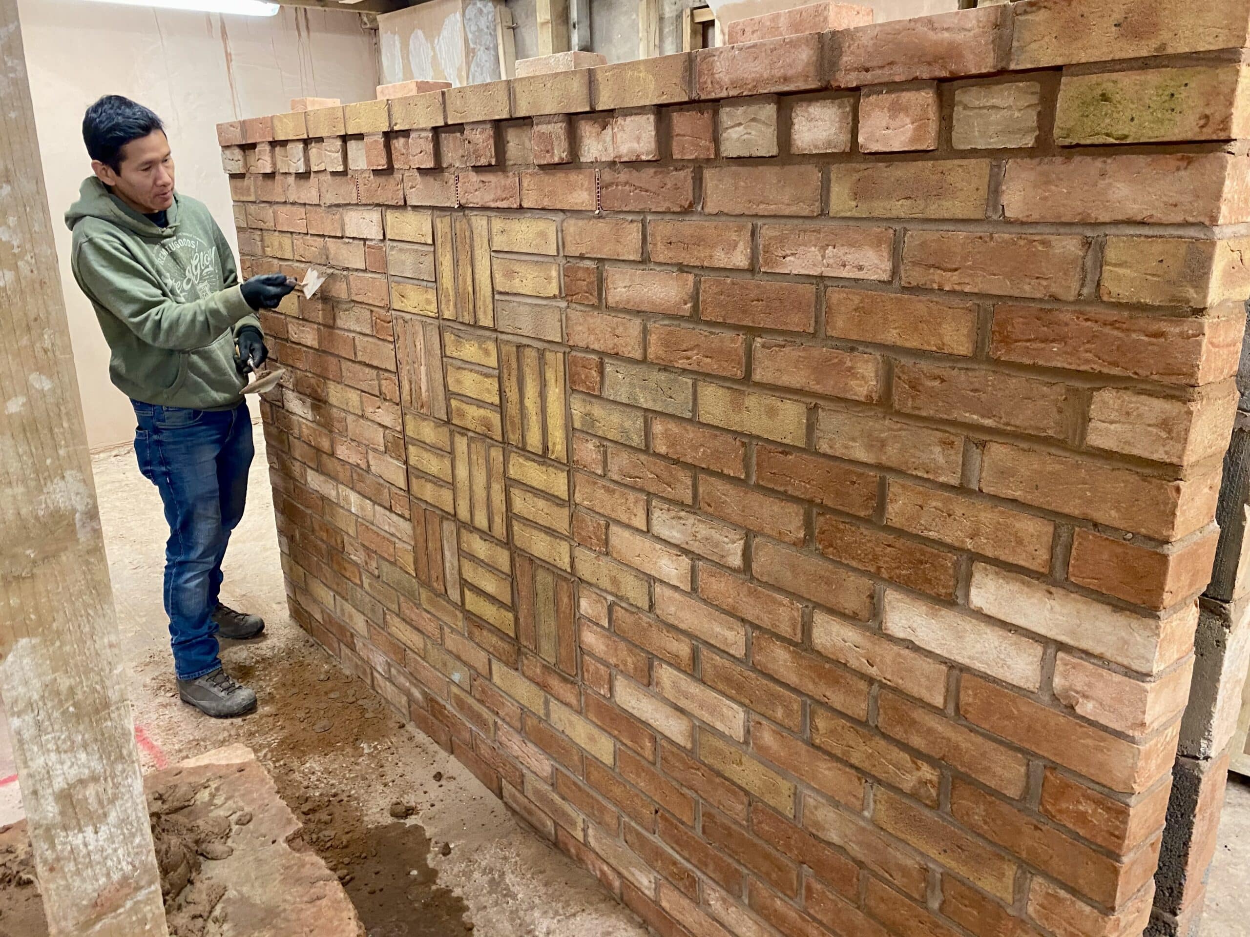 Person pointing a brick wall