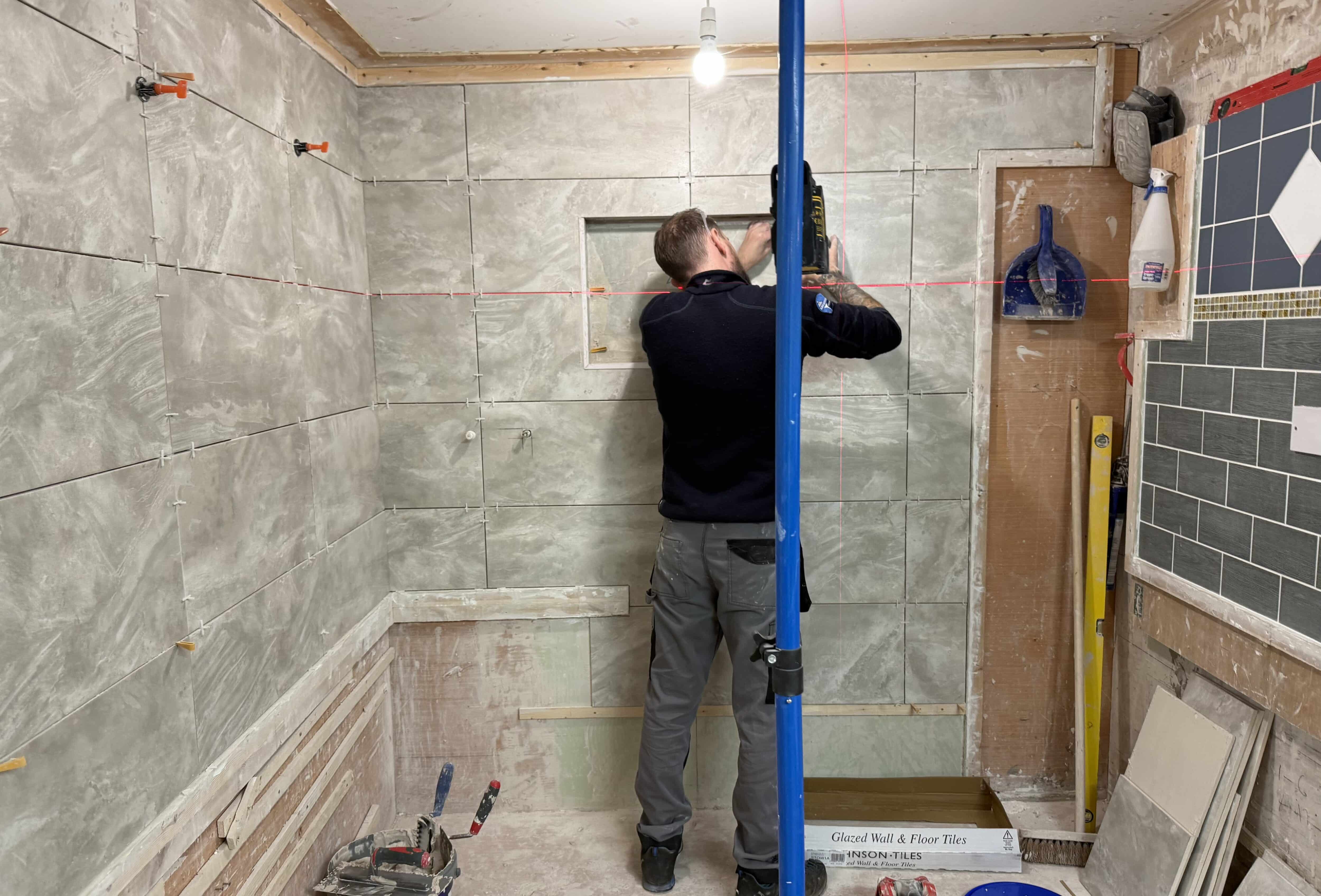 Person using a laser level on his tiling course