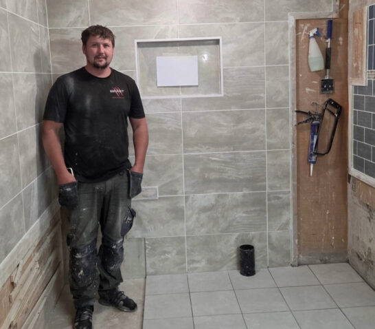 Person showing expert tiling skills with his completed tiling project