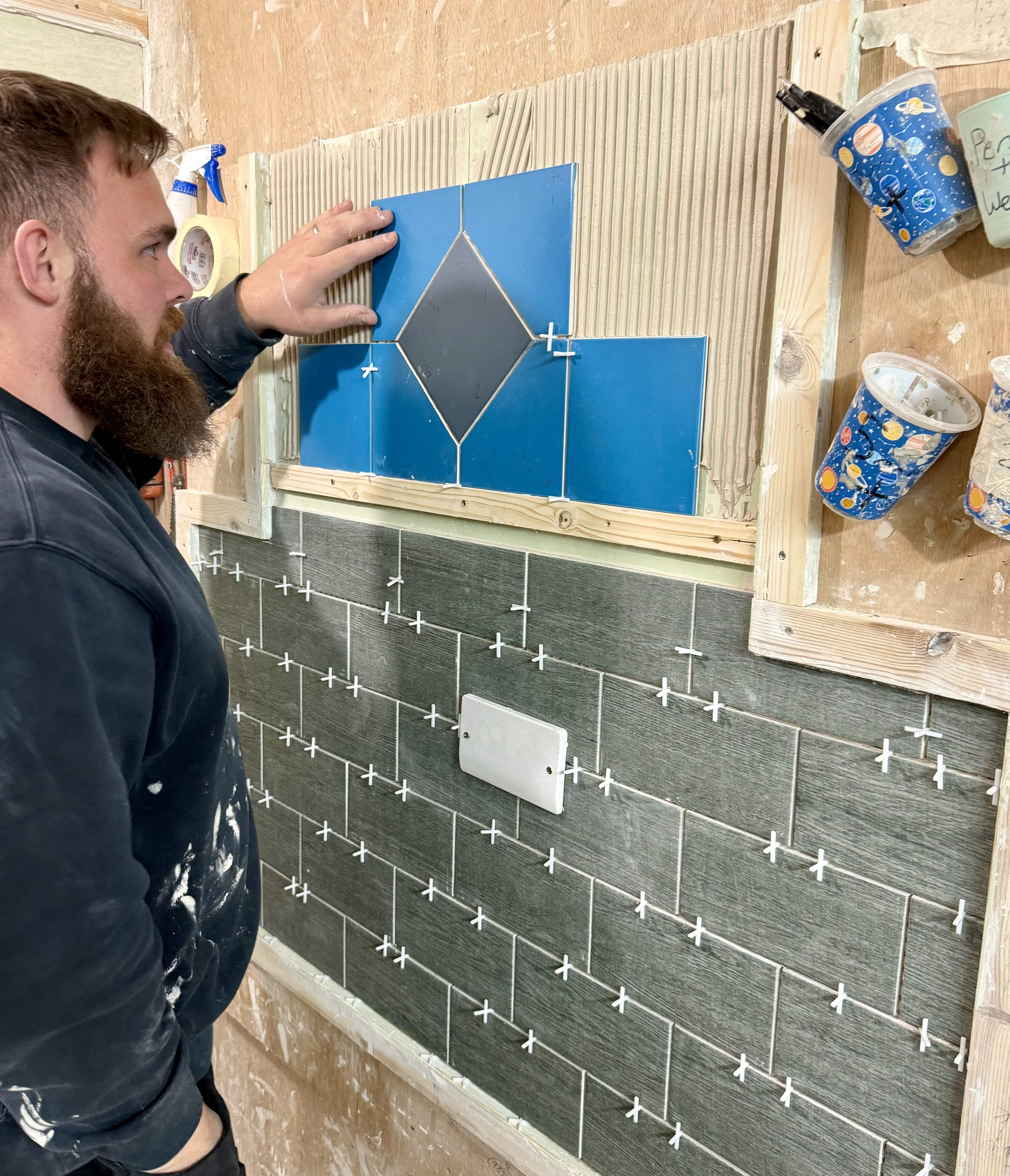 person fixing tiles as a pattern on his tiling course
