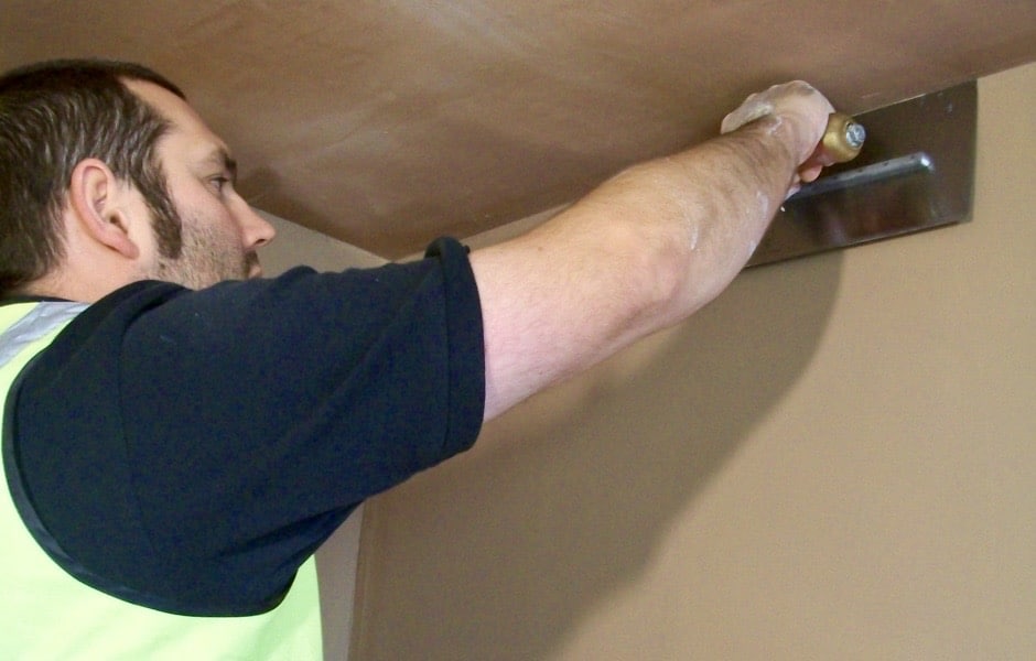 a person getting a really good finish with his trowel whilst plastering