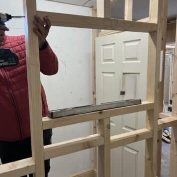 person putting a window opening into stud wall
