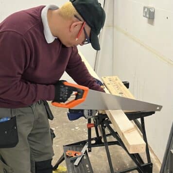 person cutting wood with a hand saw