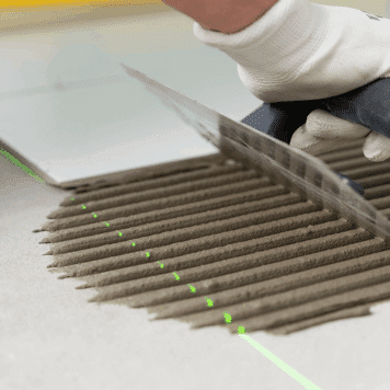 person spreading tile adhesive using a trowel