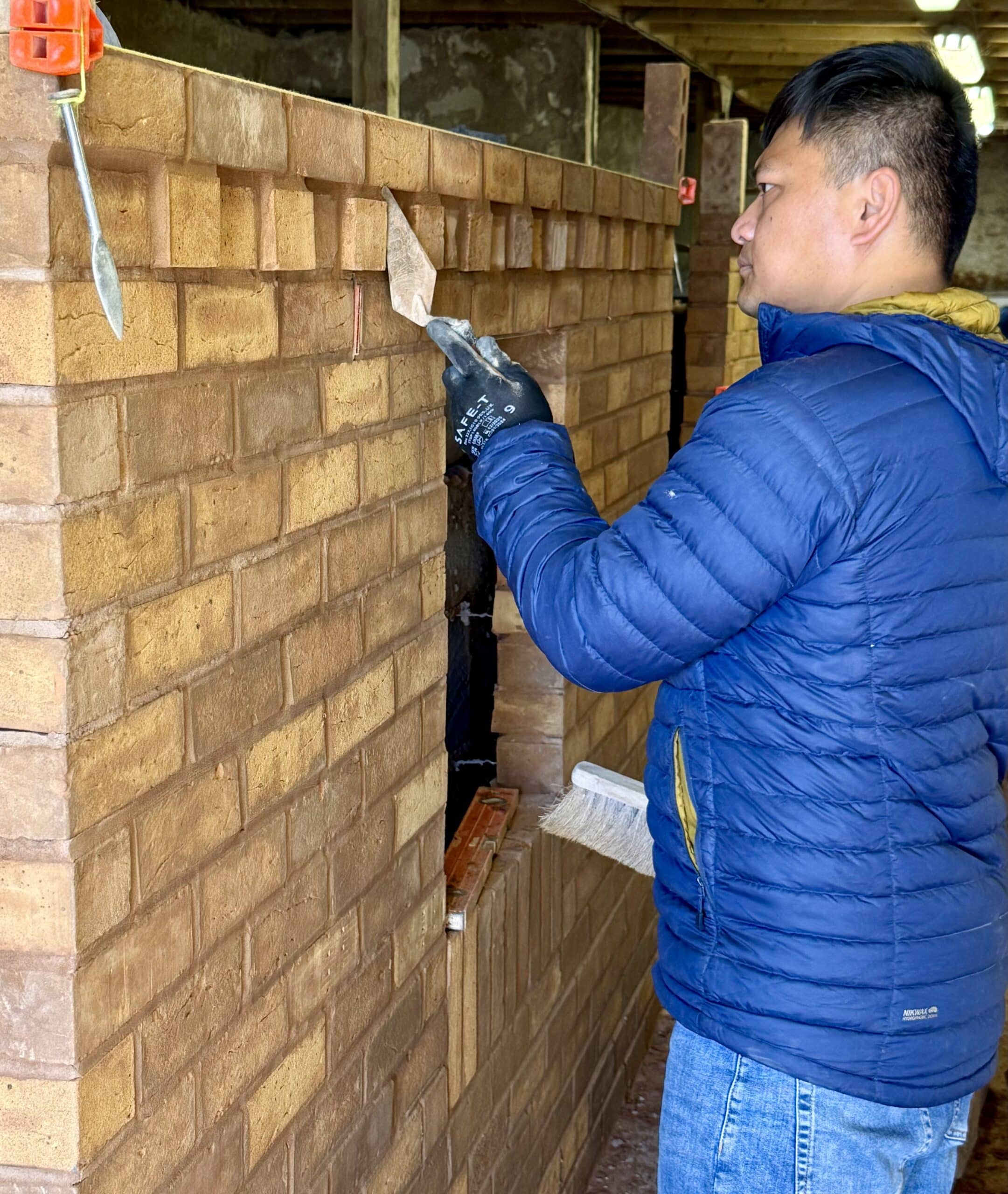 Person building a brick wall and pointing brickwork