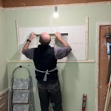 Person practicing tiling around and inside a window opening on an expert tiling course in Stoke-on-Trent