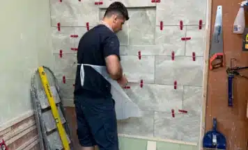 Student using tile levelling system on his tiling course in UK