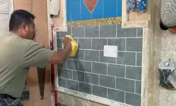 Student cleaning his tiles on his tiling course in UK