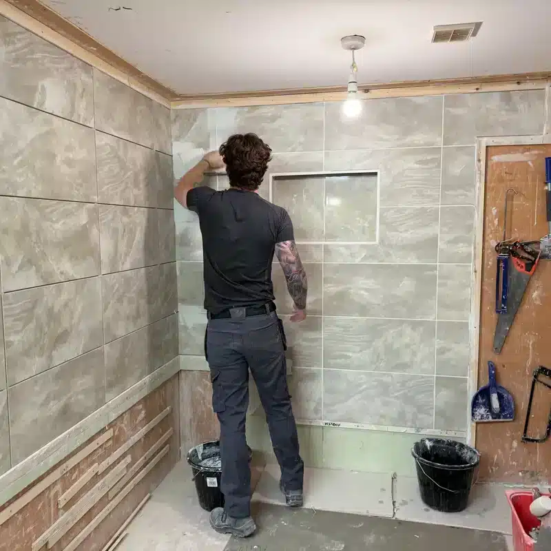 person grouting a wall on his tiling course
