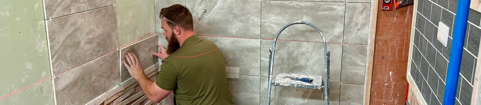 Person fixing a large format tile to a wall