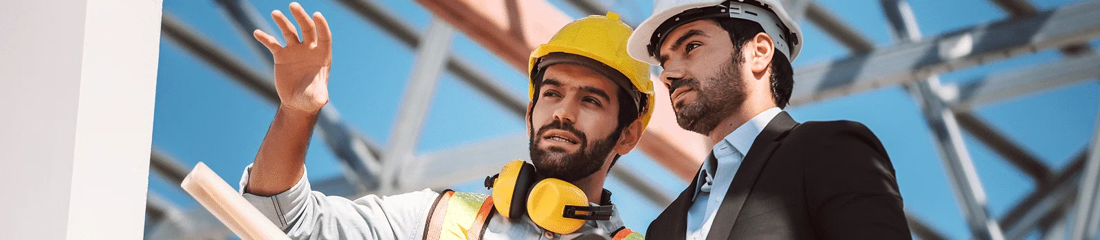 two people wearing hardhats discussing building work