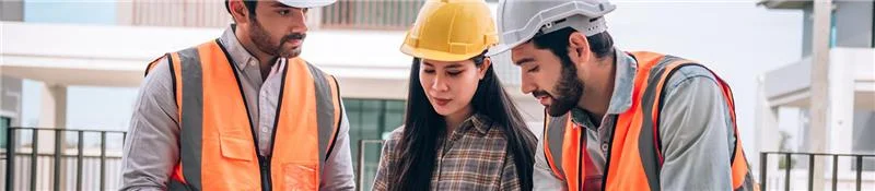 two men and a lady wearing hardhats looking at building plans