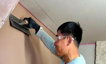 person using his trowel to plaster a wall